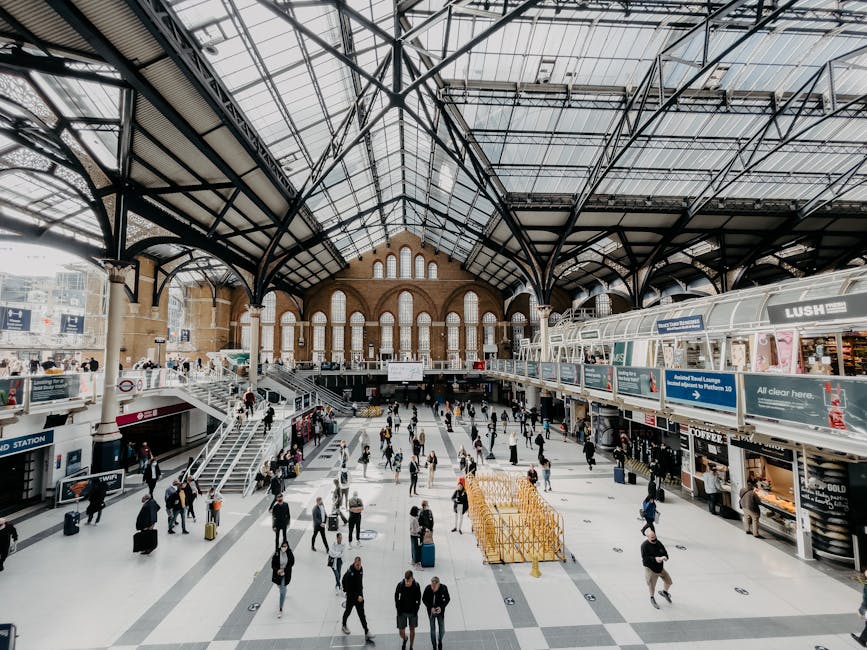 The image depicts an interior view of a transportation or railway station with a prominent brick wall displaying a large illuminated sign that reads 'WATERLOO' in capital letters, accompanied by a cir